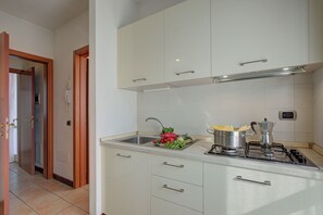 A kitchen with white cabinets, a stainless steel sink, and a gas stove. - Porto Letizia Ortensia 6, Porlezza, Italy (Porlezza)
