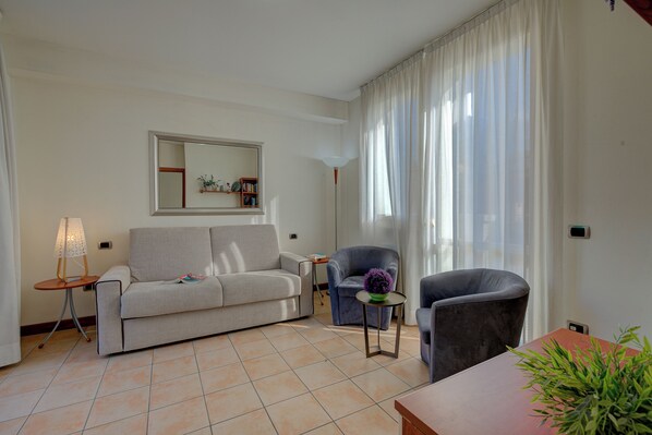 A living room with a sofa, two armchairs, a small table with a lamp, and a potted plant. - Porto Letizia Ortensia 6, Porlezza, Italy (Porlezza)