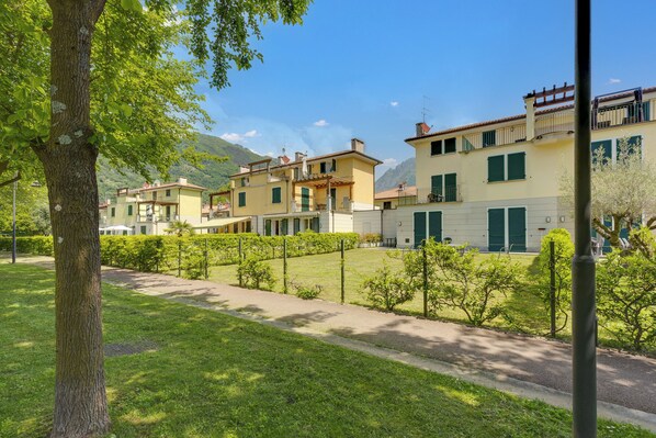 Un immeuble résidentiel doté de nombreux balcons, d’une pelouse bien entretenue et surplombant un paysage montagneux.