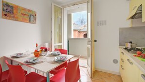 Zona de dinar amb taula preparada per a quatre, cadires vermelles i un quadre a la paret.