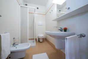 Een bad/douchecombinatie, een bidet, handdoeken