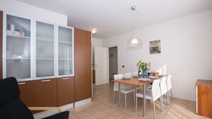 Eine moderne Küche mit Essbereich, ausgestattet mit einem Holzkabinett mit Milchglas-Türen, einem Esstisch mit Stühlen und einer Pendelleuchte.