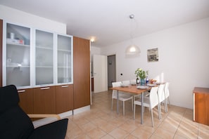 Een moderne keuken met een eethoek, met een houten kast met glaspanelen, een eettafel met stoelen en een hanglamp.