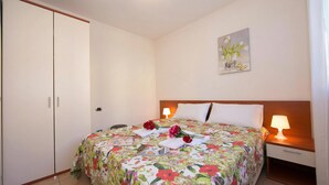 Ein Schlafzimmer mit einem Bett, Nachttischlampen, einem Nachttisch, einem Kleiderschrank und einem Bild an der Wand.