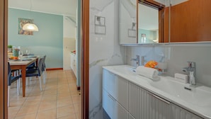 A modern bathroom with a marble sink, a large mirror, and a wooden cabinet.