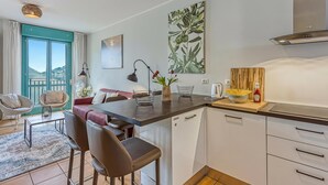 Une cuisine moderne dotée d’un îlot central, de meubles blancs et offrant une vue sur l’extérieur.