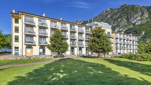 Un hôtel à plusieurs étages doté de balcons, d’une cour intérieure et surplombant un paysage montagneux.