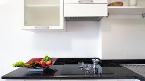 Uma cozinha moderna com armários brancos, bancada preta e fogão embutido.