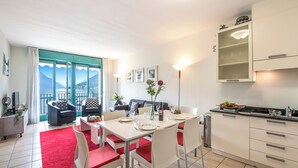 Una cucina moderna con mobili bianchi e un'area pranzo con un tappeto rosso e sedie bianche.