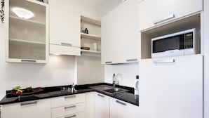Una cucina moderna con mobili bianchi, un piano di lavoro nero e un forno a microonde integrato.