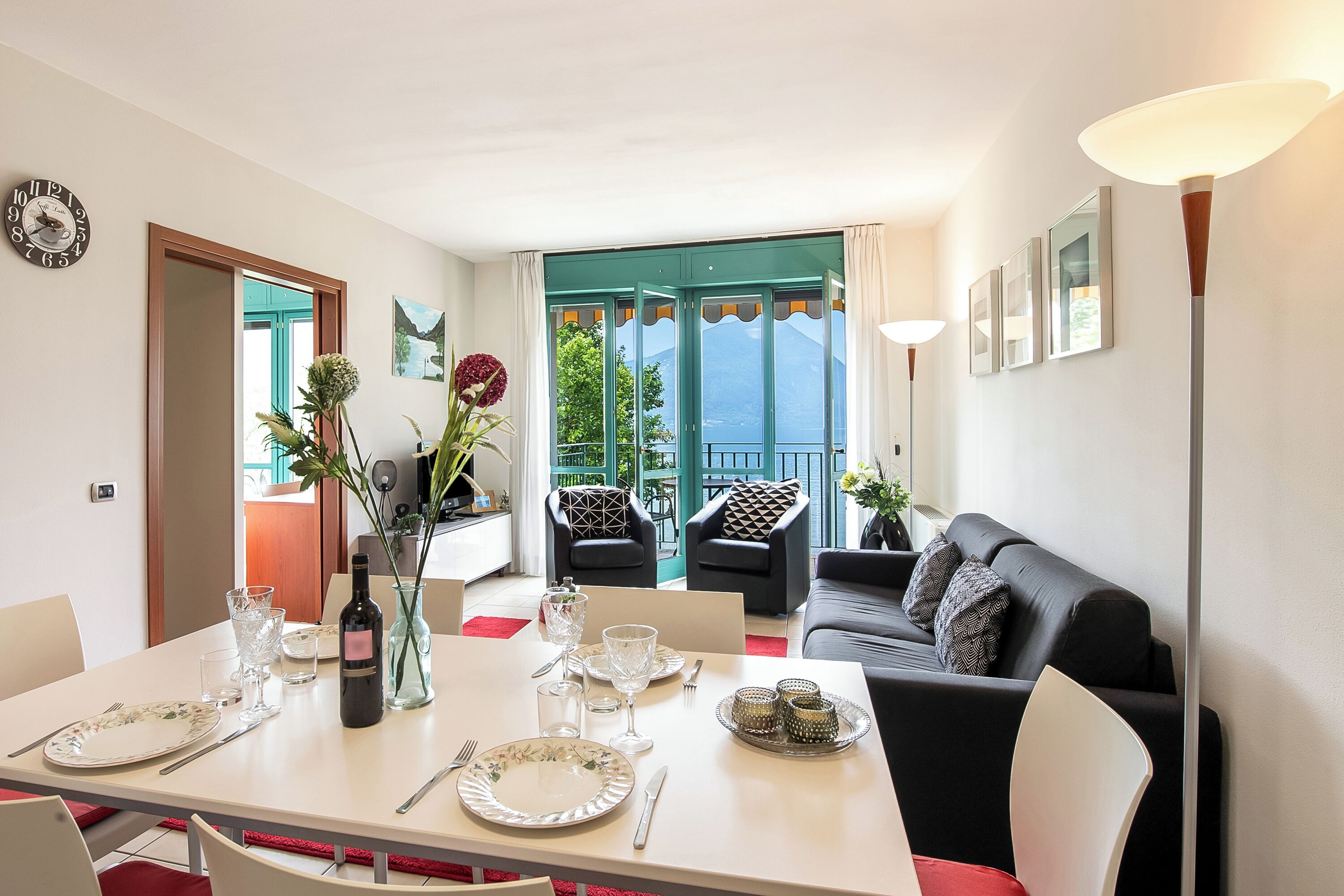 A dining area with a table set for two, a sofa, and a view of the outdoors.