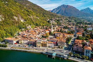 Un pueblo con un río, edificios y montañas al fondo.