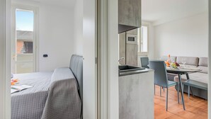 A modern room with a bed, a kitchenette, and a dining area. - Porto Letizia Iris 3, Porlezza, Italy (Porlezza)