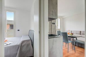 A modern room with a bed, a kitchenette, and a dining area.