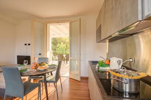 Une cuisine moderne avec un coin repas, une vue sur la verdure à l’extérieur et une casserole de pâtes sur le plan de travail.