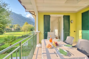 A balcony with a table set for two, overlooking a mountainous landscape. - Porto Letizia Iris 3, Porlezza, Italy (Porlezza)