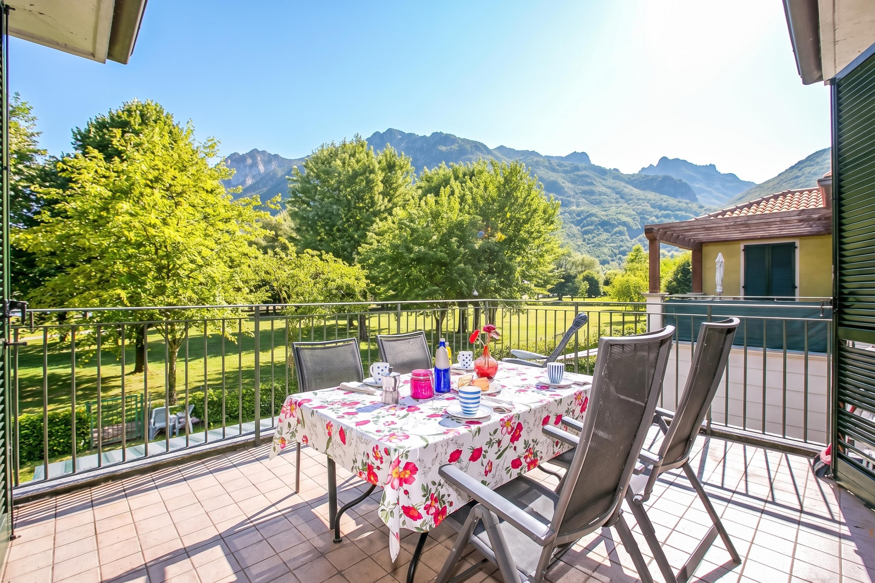 A balcony with a table set for dining, overlooking a mountainous landscape.