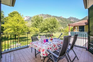A balcony with a table set for dining, chairs, and a view of mountains.
