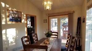 A dining room with a long wooden table, six chairs, a chandelier, and a painting on the wall. - Eagle Cliff Cottage  Sleeps 6 ((20-NCD0244) (Estes Park)