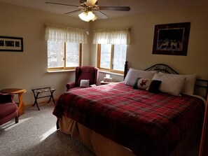 Ein Schlafzimmer mit einem großen Bett, einem Sessel, einem kleinen Tisch und einem Deckenventilator.