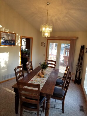 Ein Esszimmer mit Holztisch, Stühlen, einer Kandelaber und einem Bild an der Wand.