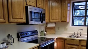 A kitchen with wooden cabinets, a stainless steel microwave, a stove, and a sink. - Eagle Cliff Cottage  Sleeps 6 ((20-NCD0244) (Estes Park)