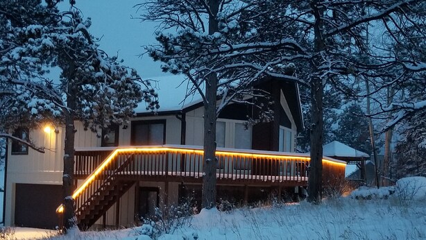A snow-covered landscape with a wooden deck and a building with a staircase. - Eagle Cliff Cottage  Sleeps 6 ((20-NCD0244) (Estes Park)