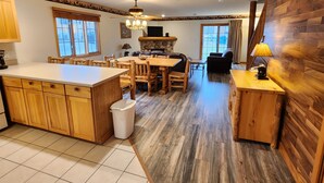 Eine geräumige Küche mit einer großen Kochinsel, Holzschränken und einem Kamin aus Stein.