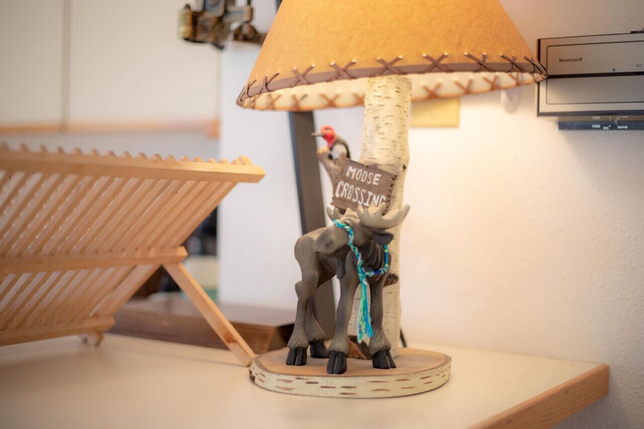Una lámpara con base de madera y un cartel que dice "MOOSE CROSSING".