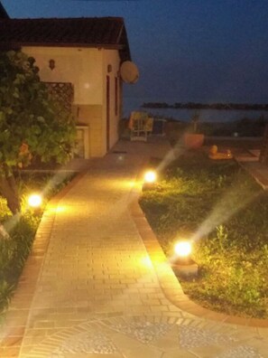 A pathway leading to a building with a tiled roof and a small porch area. - The beach house (Ortona)