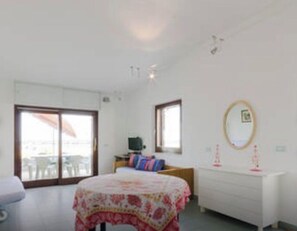 A bedroom with a bed, a dresser, a desk, and a chair.
