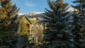 A lodge with a green roof, surrounded by snow-covered mountains and evergreen trees. - Luxury 3Br TH- Private Hot Tub/AC/Pool/Bike Storage (Whistler)