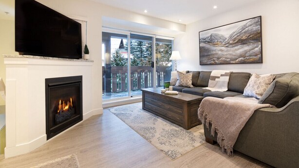A modern living room with a fireplace, a large flat-screen TV, a sofa, and a painting on the wall. - Luxury 3Br TH- Private Hot Tub/AC/Pool/Bike Storage (Whistler)