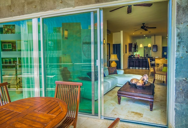 A modern living room with a glass sliding door, a wooden dining table, and a sofa.