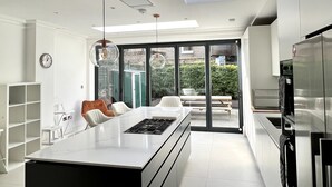 A modern kitchen with a central island, built-in appliances, and a skylight. - Beautiful 4 bedroom Victorian family house on quiet road (London)