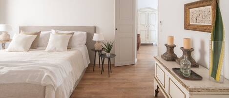 A bedroom with a bed, bedside tables, a dresser, and a door leading to another room.