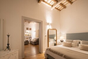 A bedroom with a large bed, a bedside table with a lamp, a mirror, and a wooden ceiling. - Dimora Botteghelle (Trapani)