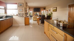 Une cuisine spacieuse avec des meubles en bois, un coin repas comprenant une table et des chaises, et un salon avec un canapé.