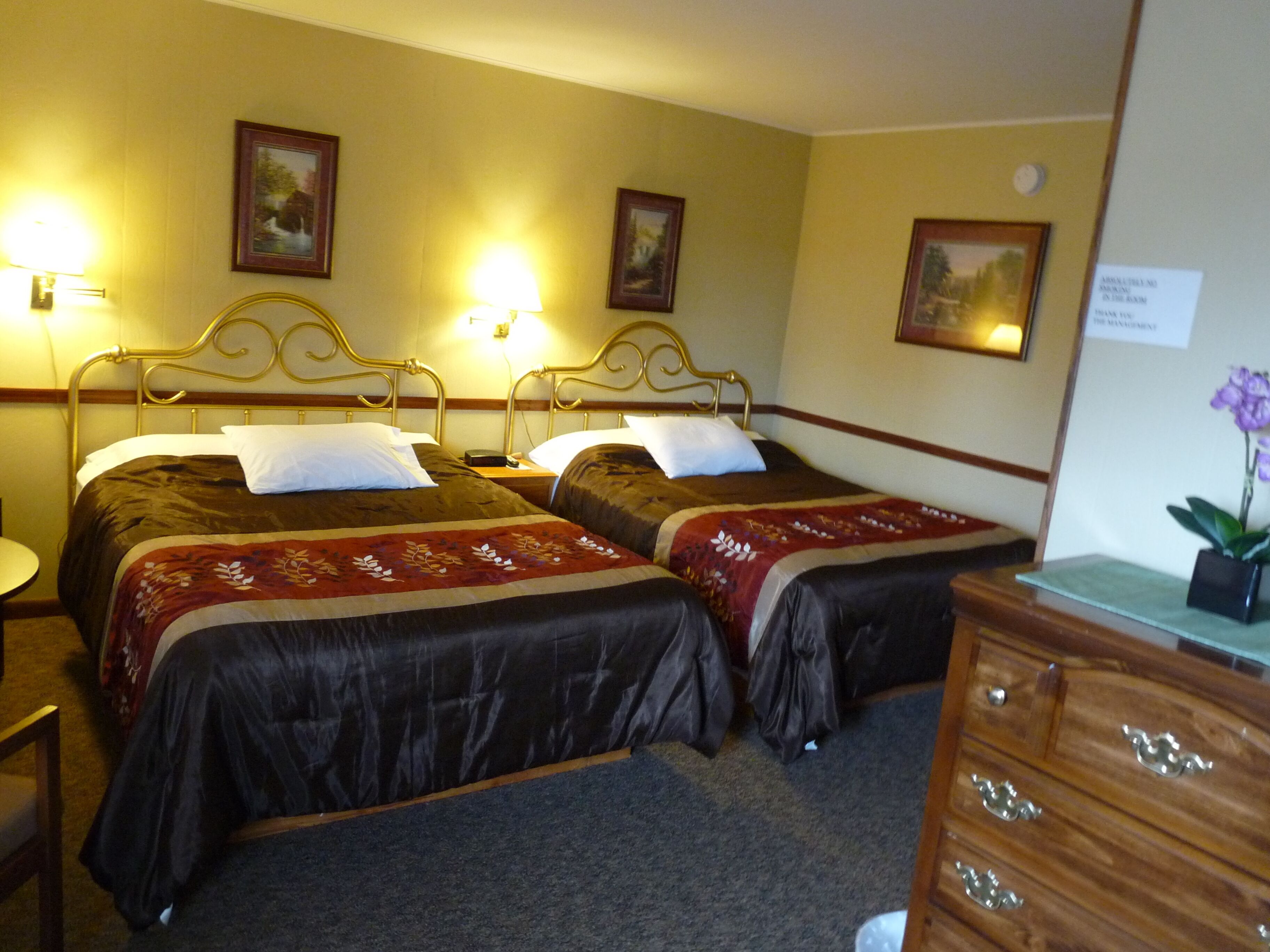 Ein Hotelzimmer mit zwei Betten, einem Holzkasten und einem kleinen Tisch.