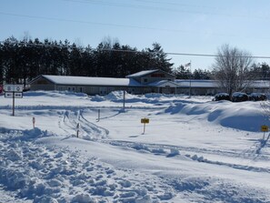 Un motel situé dans un paysage enneigé, sous un ciel dégagé, avec un panneau indiquant la direction à suivre pour rejoindre les comtés B et Q.