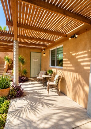 An outdoor patio with a wooden pergola, a door labeled 'Studio,' and a table with chairs. - Studio: fast internet, kitchenette, walk to beach (Todos Santos)