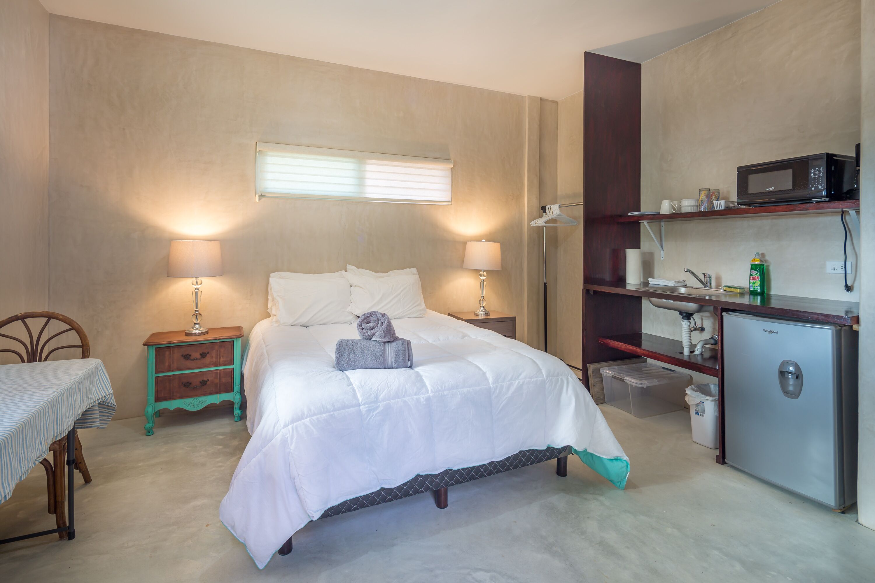 Ein Schlafzimmer mit Bett, Nachttischen, Schreibtisch, Kleiderschrank, Mikrowelle und Kühlschrank.