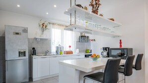 A modern kitchen with a central island, stainless steel appliances, and a microwave. - Villa Delle Rondini with private pool (Bratulici)