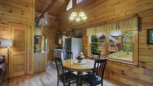 A wooden cabin interior with a dining table, chairs, a chandelier, and a view of the outside. - Book NOW and receive tickets to Dollywood, Anakeesta and many more (Gatlinburg)