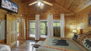 A wooden cabin with a bed, a television, and a ceiling fan. - Book NOW and receive tickets to Dollywood, Anakeesta and many more (Gatlinburg)