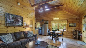 A wooden cabin interior with a living room, dining area, kitchen, and a large window. - Book NOW and receive tickets to Dollywood, Anakeesta and many more (Gatlinburg)