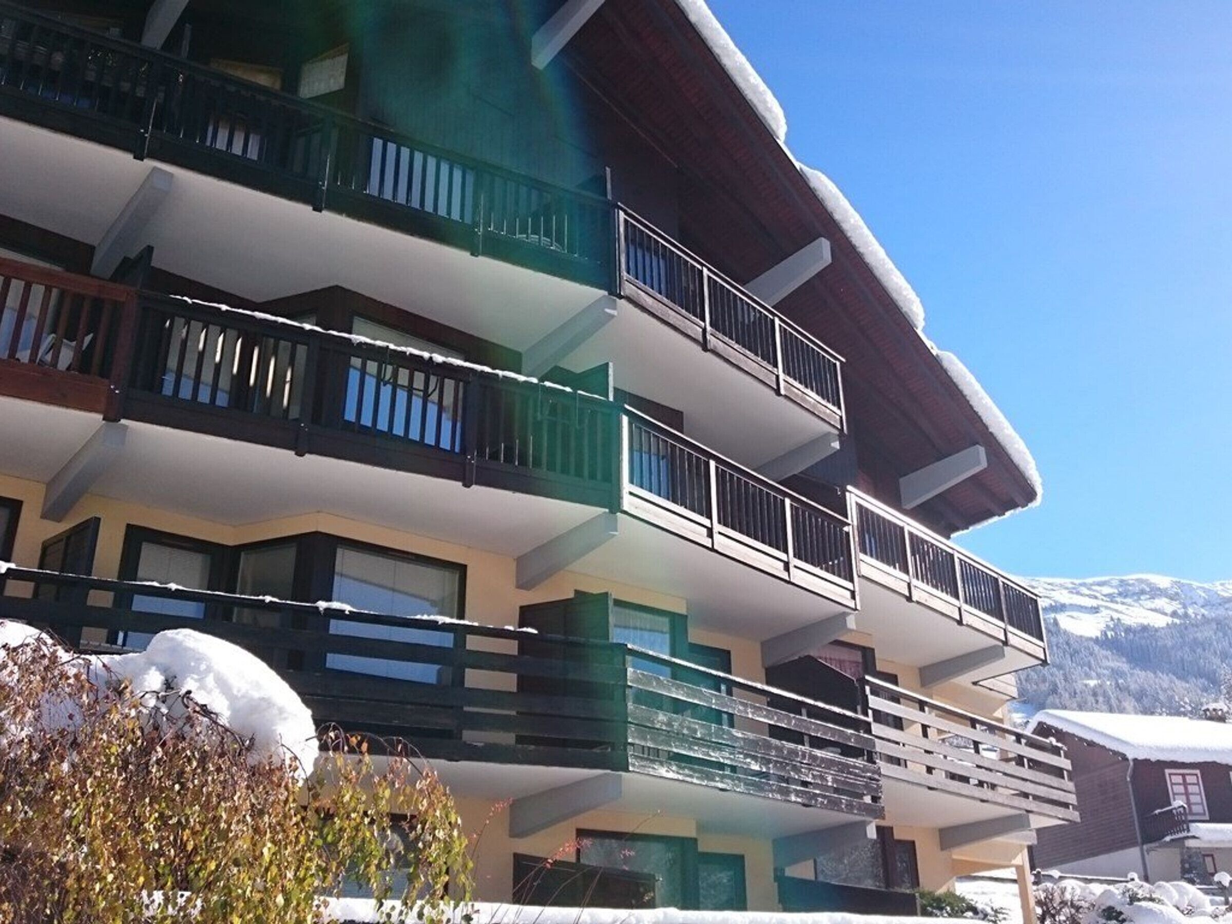Ein mehrgeschossiges Gebäude mit Balkonen, umgeben von schneebedeckten Bergen.
