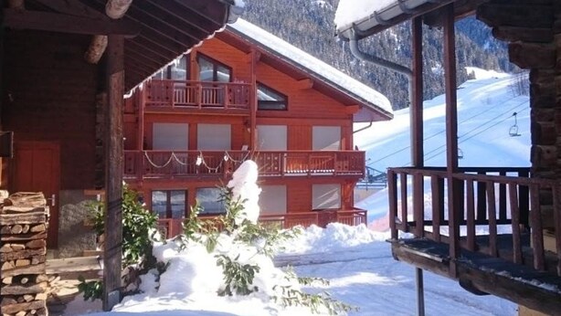 A wooden chalet with a balcony, surrounded by snow-covered ground and a ski slope in the background. - Cozy Ski-In/Ski-Out Apartment for 4 in Arêches-Beaufort, Terrace, Great Amenities (Arêches-Beaufort)