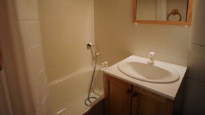 A bathroom with a bathtub, a sink, and a mirror. - Cozy Ski-In/Ski-Out Apartment for 4 in Arêches-Beaufort, Terrace, Great Amenities (Arêches-Beaufort)