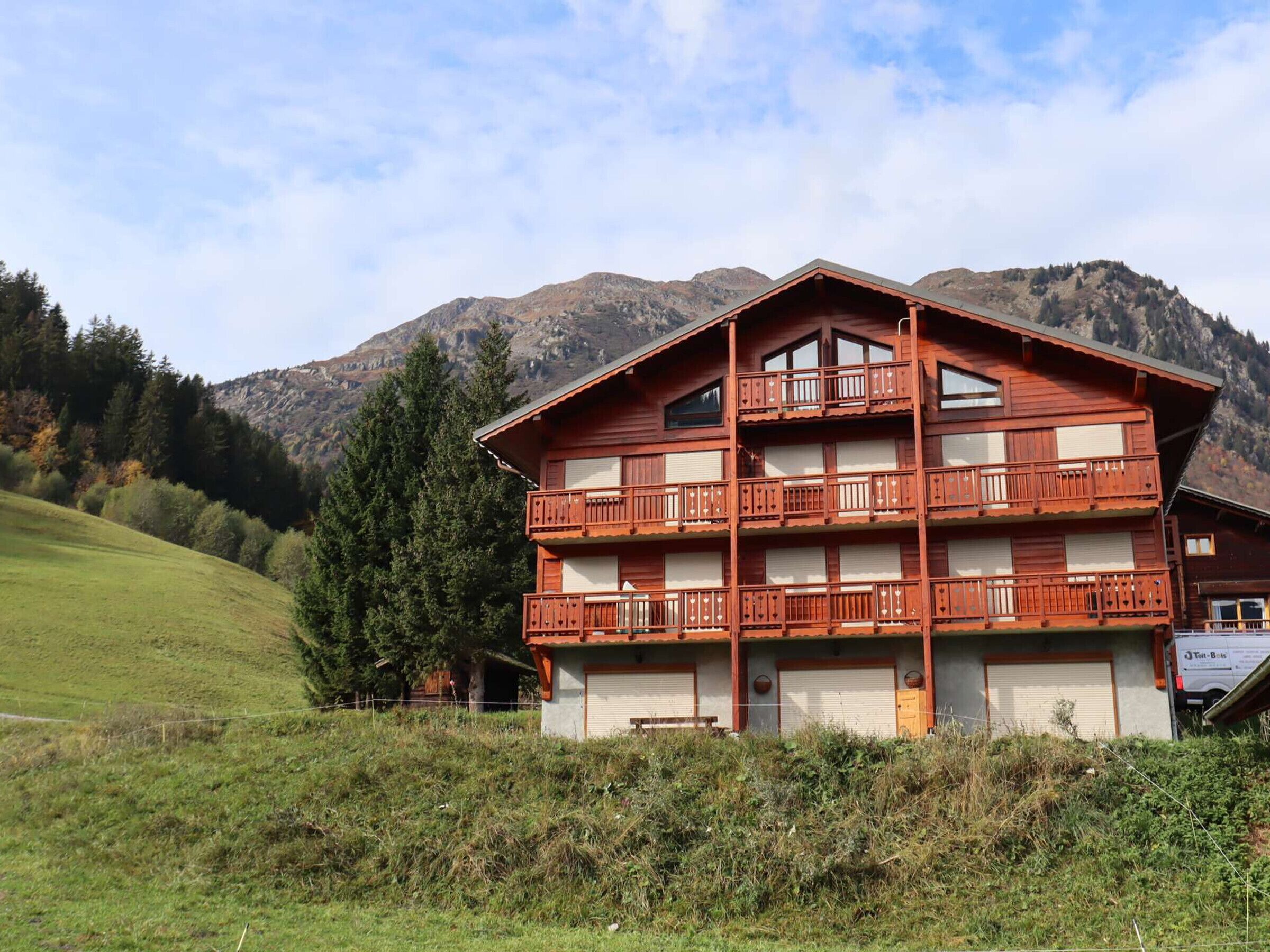 A multi-story wooden building with balconies, set against a mountainous backdrop.